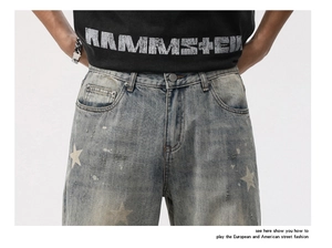 Détail du jean délavé vintage avec imprimés étoiles et effets déchirés usés