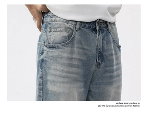 Close-up of light blue washed denim jeans with metal button and whiskering texture detail