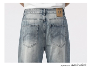 Detail view of denim jeans featuring back pockets with V-shaped stitching and leather waist tag