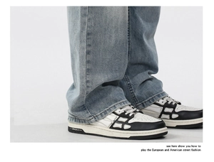 Detail of light blue washed loose jeans paired with black and white retro street sneakers