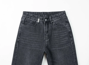 Détail de la taille en denim avec bouton en métal argenté et étiquette tissée blanche