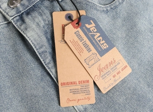 Detailed macro view of light blue denim fabric with metal button and brand hangtag