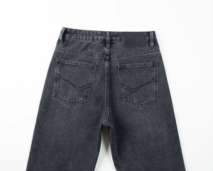 Détail d'un jean en denim gris foncé délavé avec écusson en cuir au dos et surpiqûres