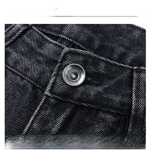 Dettaglio macro del bottone in metallo argento su jeans neri lavati con dettagli in vita