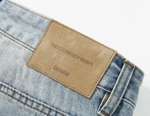 Dettaglio della vita in denim azzurro con etichetta in finta pelle marrone e cuciture