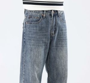Détail du jean denim délavé bleu clair avec design classique à cinq poches et bouton en laiton