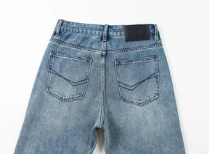 Detail of light blue washed denim jeans showing the leather back patch and pockets