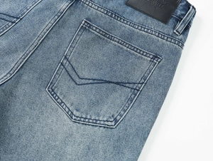 Detailed close-up of light blue washed denim jeans showing back pocket and leather brand tag
