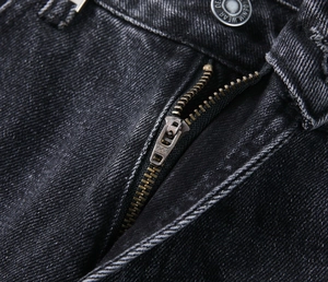 Détail du jean denim noir délavé avec fermeture éclair YKK et bouton denim wear