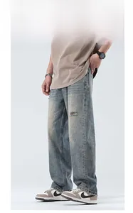 Detail of light blue washed straight denim jeans for men with distressed knee rips
