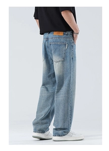 Détail d'un jean bleu clair délavé avec écusson en cuir et coutures sur la poche arrière