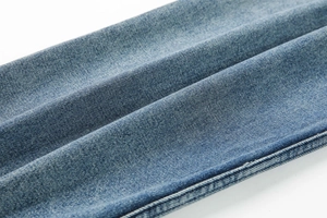 Detail of light blue heavy washed denim fabric with visible twill texture and side stitching
