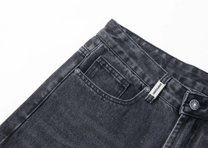 Gros plan détaillé de la taille d'un jean délavé gris foncé avec rivets et logo gravé