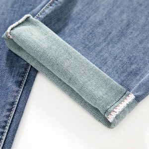 Classic slim fit light blue denim jeans showing cuffed hem with red selvedge detail