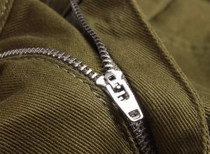 Vue détaillée de la fermeture éclair en métal argenté sur un short en denim olive