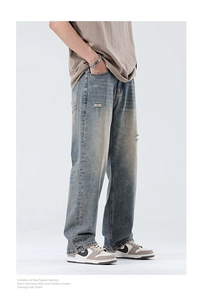 Detail showing vintage blue wash and distressed texture on men's wide-leg denim jeans