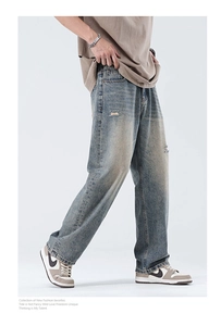 Detail view of retro blue distressed denim jeans with washed effect and loose fit