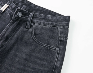 Détail de jean délavé montrant les ferrures métalliques et la texture du tissu