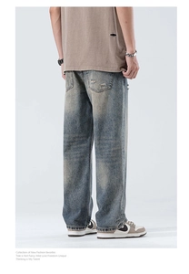 Detail of distressed back pocket and retro washed blue texture on men's wide-leg jeans