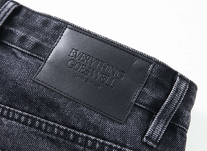Gros plan détaillé de l'étiquette en cuir noir sur la taille du jean noir délavé