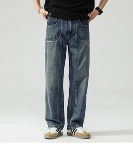 Detail view of washed dark blue denim trousers with vintage seam lines and relaxed fit