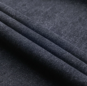 Gros plan du tissu denim délavé épais montrant la texture sergée et les plis souples