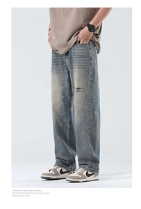 Detail of light blue straight-leg denim jeans featuring vintage wash and distressed ripped knees
