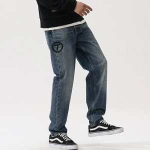 Detail of vintage blue straight-leg jeans with round logo patch and heavy wash finish