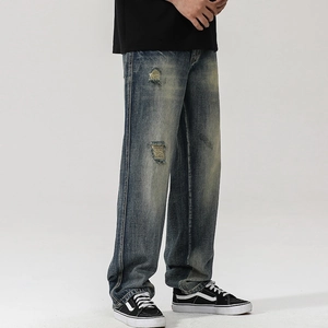 Vue détaillée du jean denim vintage délavé avec moustaches usées et déchirures aux genoux