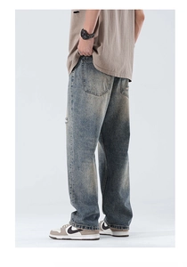 Detail of vintage blue washed denim fabric and back pocket stitching on wide-leg jeans