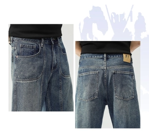 Detailed view of dark blue washed denim jeans featuring heavy stitching and leather waist tag
