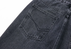 Détail du jean gris délavé montrant une poche arrière avec couture en V et finitions