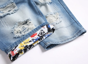 Détail d'un short en jean bleu clair délavé avec trous et doublure à motif graffiti
