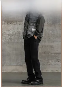 Vista laterale dei jeans svasati neri da uomo abbinati a stivali in pelle e gilet in denim