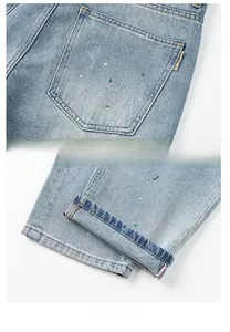 Nahaufnahme hellblauer Jeans mit Farbspritzern und orangefarbenen Kontrastnähten