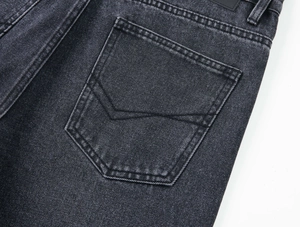 Détail de la poche arrière avec surpiqûres en V sur un jean denim noir délavé coupe droite