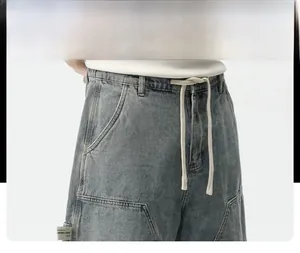 Détail du short en jean délavé avec taille à cordon et poches latérales renforcées