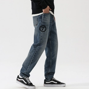 Detail of blue wash denim pants featuring a black circular number seven embroidery