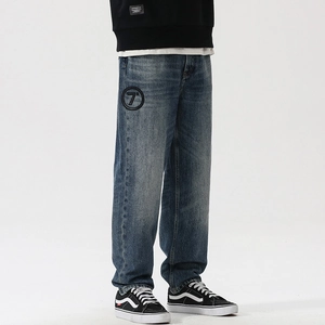 Detail of loose-fit washed blue jeans with a unique circular 7 degree black patch