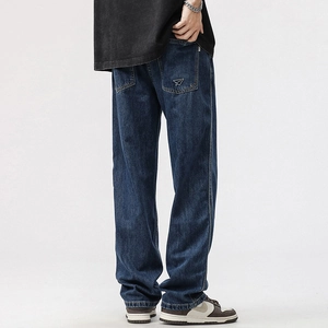 Detail of paper airplane embroidery on back pocket of washed dark blue straight jeans