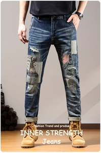 Detail of distressed men's denim jeans with patchwork embroidery and retro wash effect