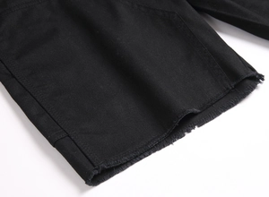Gros plan sur l'ourlet à bord franc d'un short en jean noir montrant les détails du sergé