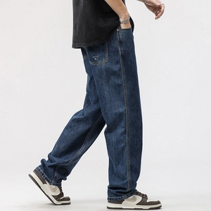 Detail showing white paper plane embroidery on the back pocket of blue denim jeans