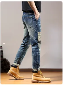 Detail view of denim jeans featuring patchwork cartoon patches and distressed ripped effects
