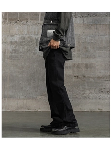 Dettaglio di jeans neri a campana e gilet in denim grigio in un contesto urban high street
