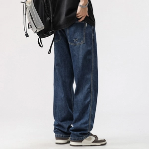 Detailed view of dark blue jeans featuring white paper plane embroidery on back pocket