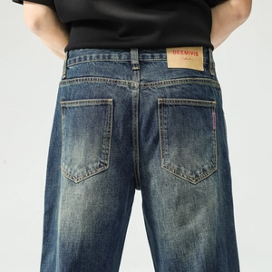 Détail d'un jean bleu foncé délavé vintage avec patch en cuir marron et étiquette tissée