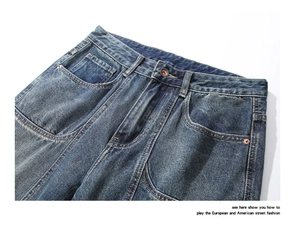 Detail view of high-waist washed dark blue jeans with copper rivets and curved pockets