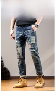 Detail of distressed jeans with patchwork embroidery, whiskers, and cuffed hems