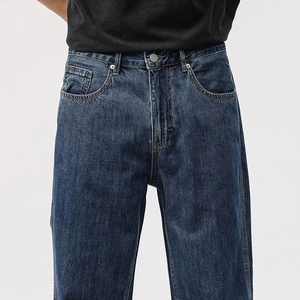 Detailed view of washed dark blue denim fabric and metal button fly on these straight jeans